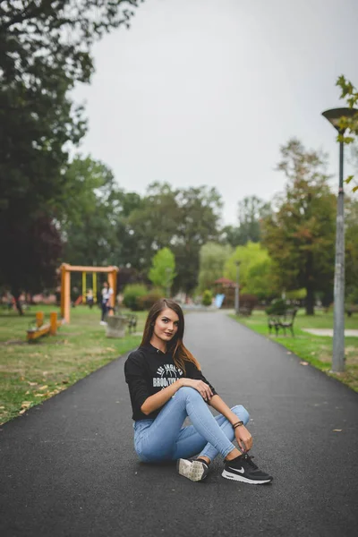Sıradan Giysiler Içindeki Genç Bir Bayanın Parkta Otururken Çekilmiş Dikey — Stok fotoğraf
