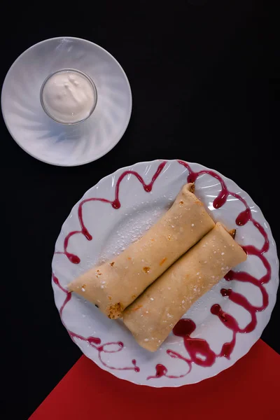 白いソースをかけた赤いシロップのロールパンケーキの垂直ショット — ストック写真