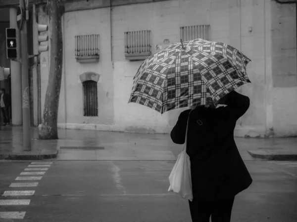 Graustufenaufnahme Von Jemandem Der Mit Einem Regenschirm Die Straße Überquert — Stockfoto