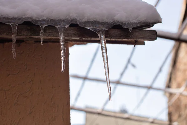 用冰冻冰柱拍摄的覆盖着雪的屋顶的特写镜头 — 图库照片