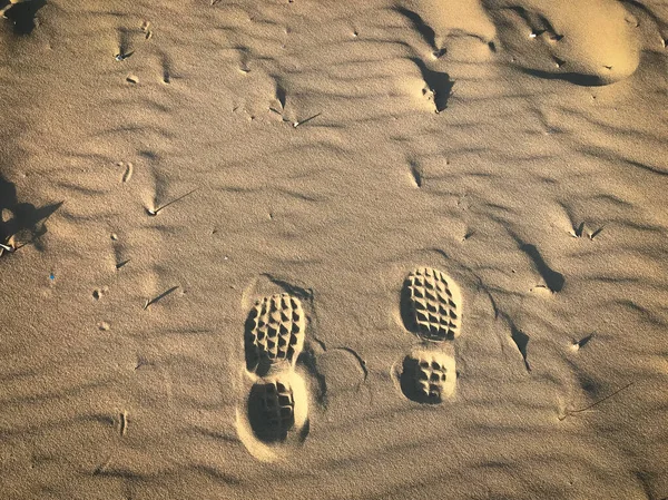 An overhead shot of shoe prints on the sand at a beach in Avola City, Sicily, Italy