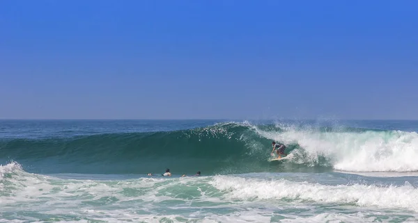 Três Surfistas Numa Onda Poderosa Sob Céu Azul Claro — Fotografia de Stock