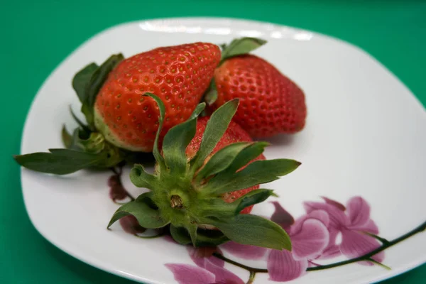 Крупный План Вкусной Клубники Белой Тарелке Розовыми Цветочными Украшениями Зеленом — стоковое фото