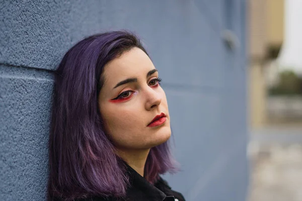 壁に紫色の髪を傾けた若いヨーロッパの女性の肖像画と悲しいことに側面を見て — ストック写真