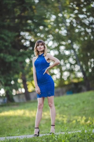 一位漂亮的金发白种女人 身穿蓝色衣服 在公园里摆姿势 — 图库照片