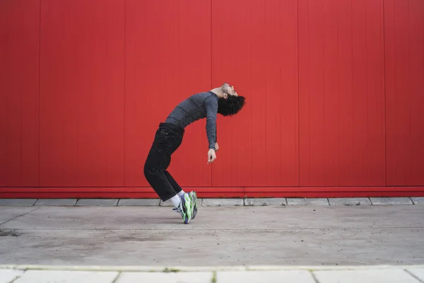 Een Blanke Krullende Man Dansend Tegen Een Rode Muur Buiten — Stockfoto
