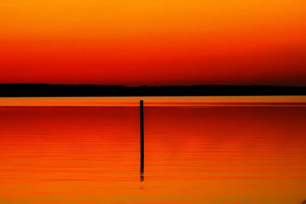 Una Silueta Palo Agua Durante Una Puesta Sol Naranja — Foto de Stock