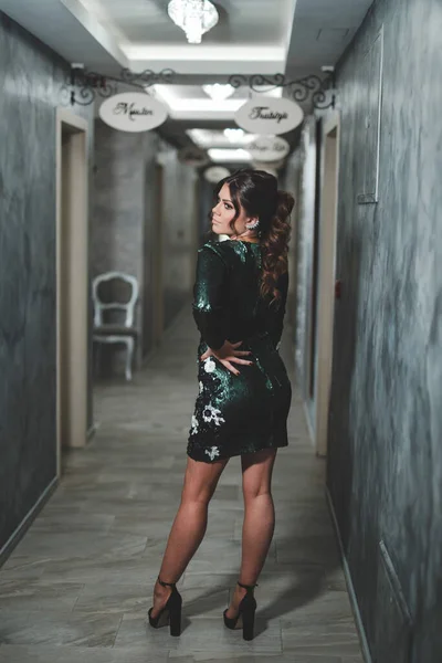 一个性感的波斯尼亚黑发女孩穿着时髦的绿色亮片连衣裙在走廊里回头看 — 图库照片