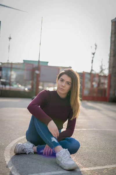 ジーンズにセーターを着て 庭のサッカーピッチに座っている大人の女性の浅い焦点 — ストック写真