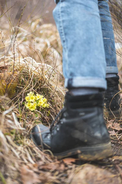 フィールド内の黄色の花の近くに汚れたブーツを着て女性の足の垂直ショット — ストック写真