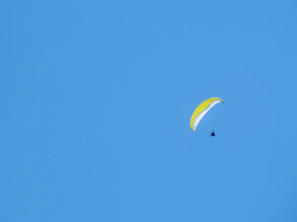 Een Paraglider Met Een Heldergele Parachute Tegen Een Helderblauwe Lucht — Stockfoto