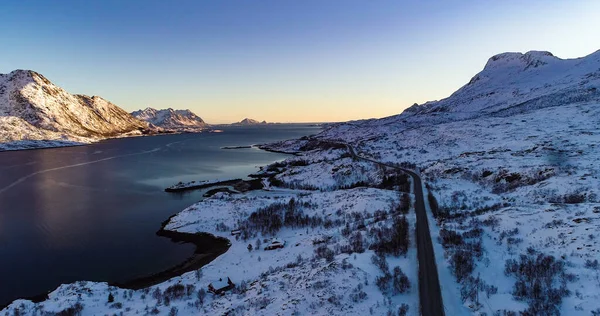 在挪威罗浮敦 空中无人驾驶飞机俯瞰着一条海岸公路 在雪山中央 天空五彩斑斓 乌云密布 — 图库照片