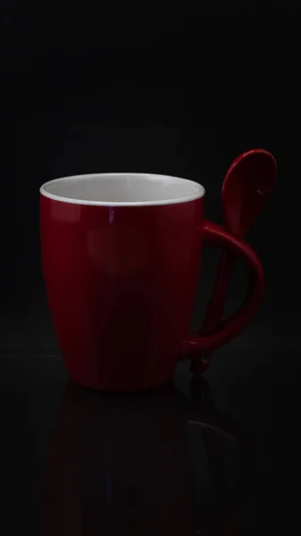 黒い背景にスプーンで赤いマグカップのクローズアップショット — ストック写真