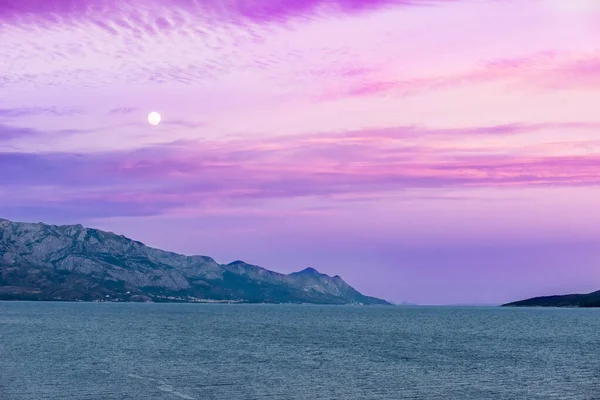 Прекрасний Вид Океан Оточений Горами Блищить Під Хмарним Фіолетовим Небом — стокове фото