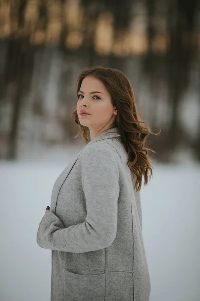 雪に覆われた冬の公園に黒いシャツ ジーンズ ジャケットを着た若い白人女性 — ストック写真