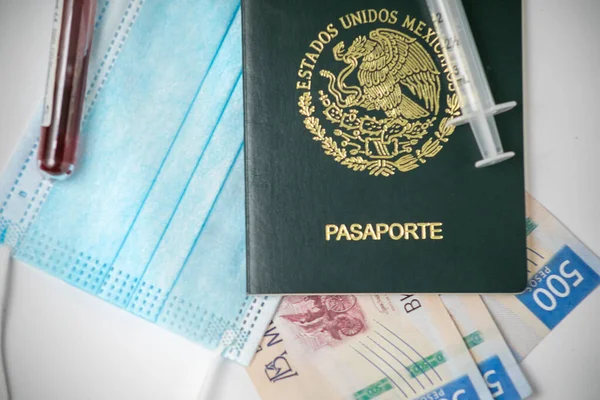 一本墨西哥护照 上面有现金帐单 桌上有注射针 上面有面罩和Covid 19血样 — 图库照片