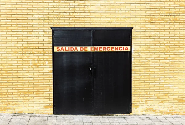 A double black emergency door with indications of a brick building