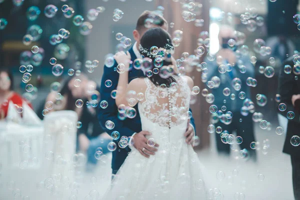 新婚夫妇在被肥皂泡环绕的婚礼庆祝活动中跳舞时的一个肤浅的焦点 — 图库照片