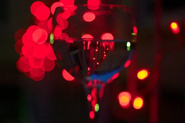 背景にカラフルなライトのついたワイングラスのクローズアップ — ストック写真