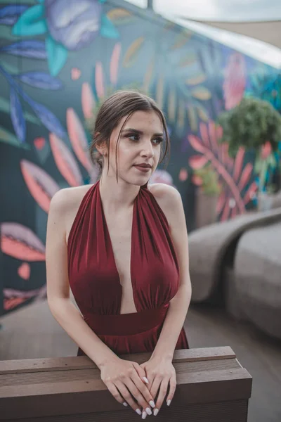 一个优雅的女人穿着红色性感晚礼服站在户外咖啡店的倒影 — 图库照片