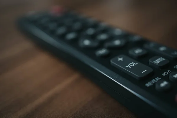 木製のテーブル ボリュームボタン上の黒いポータブルリモートコントロールのクローズアップショット — ストック写真