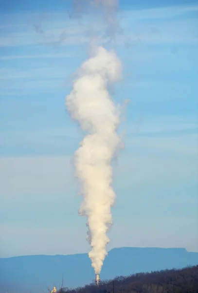 A vertical shot of industrial smoke on the sky background
