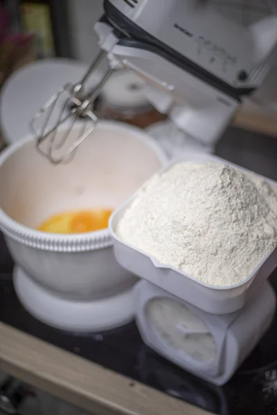 台所の卵でいっぱいのミキサーの横の測定スケールで小麦粉のトップビューのクローズアップビュー — ストック写真