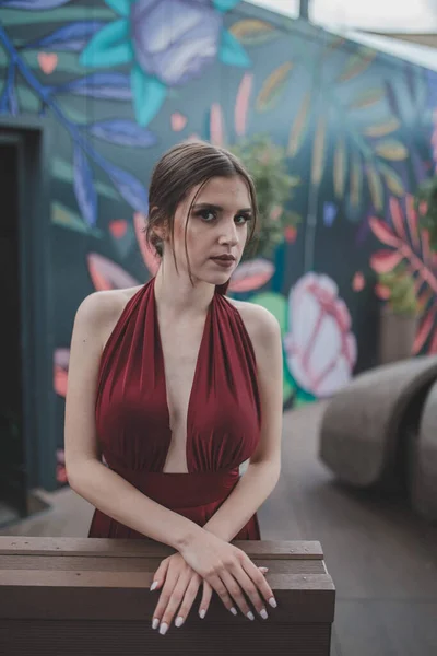 一个优雅的女人穿着红色性感晚礼服站在户外咖啡馆的照片 — 图库照片
