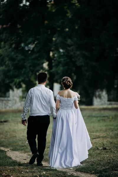 Una Vista Trasera Los Recién Casados Tomados Mano Mientras Caminan — Foto de Stock