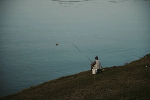 Hombre Sentado Orilla Lago Pescando Solo Día Frío Sombrío — Foto de Stock