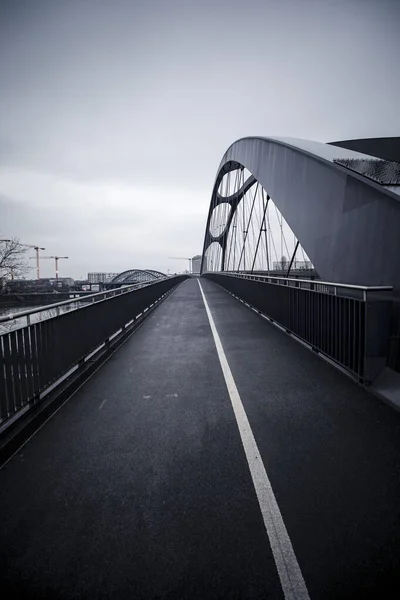 暗い空の下で鋼アーチ橋と空の道路の景色 — ストック写真