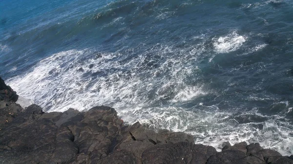 夏には岩の崖の上で波が飛び散ったり跳ねたりするのを見ることができます — ストック写真