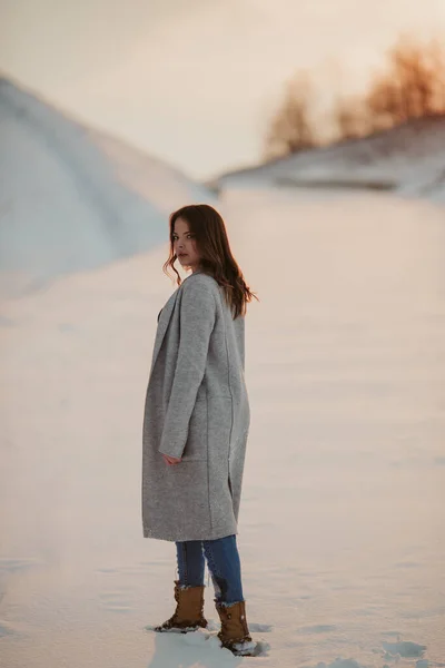 雪に覆われた森の中でコートを着てジーンズを身に着けている大人のブルネットの女性の浅い焦点 — ストック写真