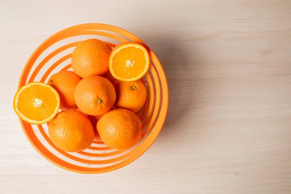 stock image A top view of a bowl with fresh oranges on a wooden surface