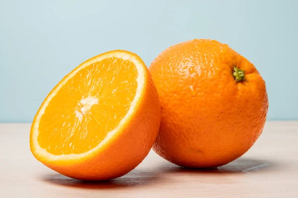 Zbliżenie Pysznych Pociętych Pomarańczy Drewnianym Stole Pastelowym Niebieskim Tle — Zdjęcie stockowe