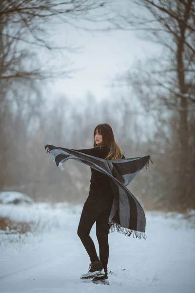 Young Woman Moving Her Oversized Blanket Scarf While Standing Snowy — стоковое фото