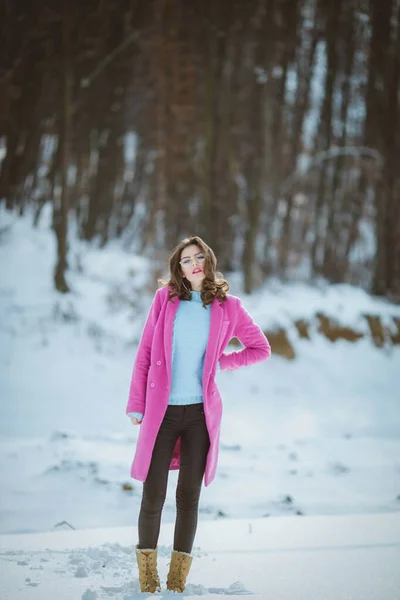 若いですブルネットの女の子のフルボディショットで眼鏡をかけていますピンクのコートを身に着けています雪の中に立って — ストック写真