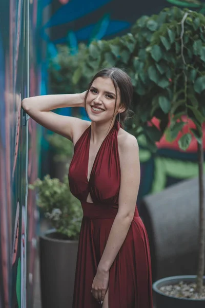 一个穿着红色衣服 靠在室外咖啡馆墙上的快乐女人的肤浅的焦点 — 图库照片