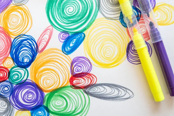 A closeup shot of colorful spiral drawings with yellow and purple markers