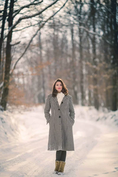 若いですブルネットの女の子のフルボディショットでAスタイリッシュな冬の衣装冬に森の道を歩く — ストック写真