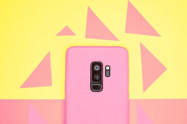 Renkli Bir Yüzeyde Üçgenlerle Çevrili Pembe Bir Cep Telefonunun Yakın — Stok fotoğraf