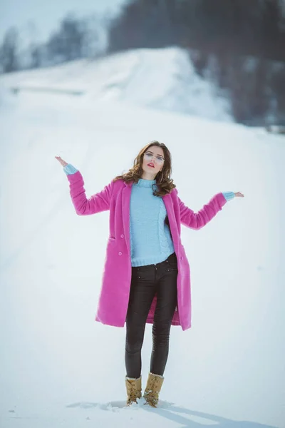 フルボディショットのA若いですブルネット女の子とともに眼鏡でザ雪の森の中でピンクのコートを着て — ストック写真