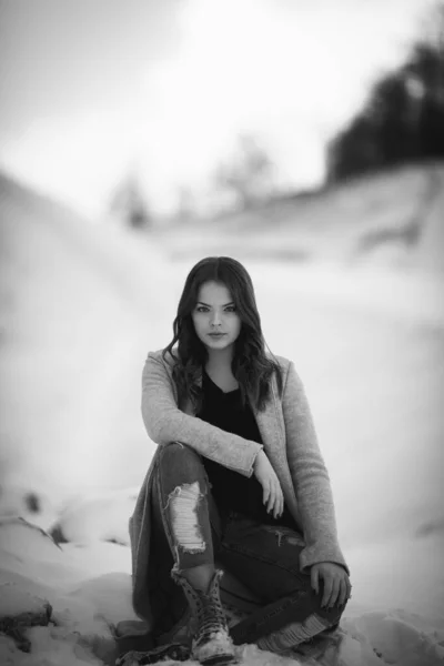 Monochromatyczne Ujęcie Pięknej Kobiety Siedzącej Śnieżnym Lesie Długim Płaszczu Podartych — Zdjęcie stockowe