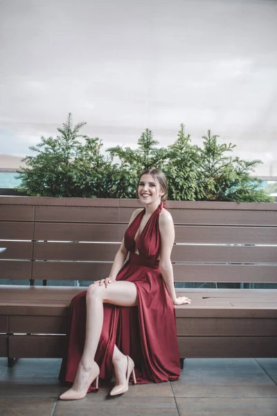 Μια Χαμογελαστή Όμορφη Μελαχρινή Γυναίκα Ένα Φανταχτερό Κόκκινο Φόρεμα Κάθεται — Φωτογραφία Αρχείου