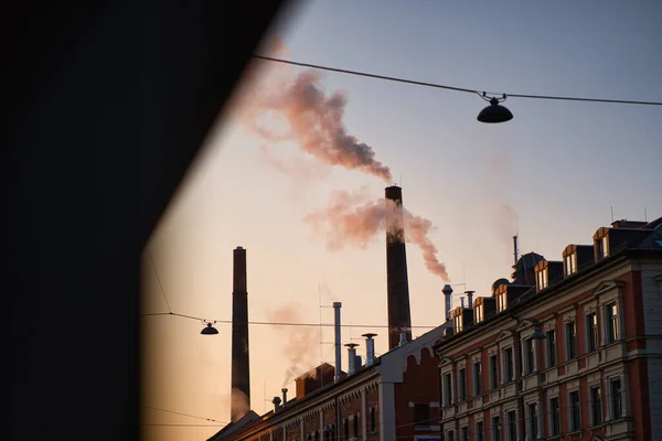 朝の光の中で工場の煙突から煙が立ち上がる ミュンヘンのビール醸造所です — ストック写真