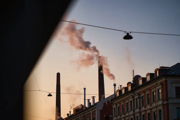 朝の光の中で工場の煙突から煙が立ち上がる ミュンヘンのビール醸造所です — ストック写真