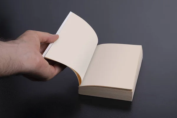 暗い黒の背景に空白のページを持つ小説の本を開く男の手 クリッピングパスが含まれています — ストック写真