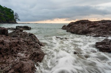 PANAMA, PANAMA - Apr 25, 2021: Wave breaking on a rocky Beach, sunset clipart