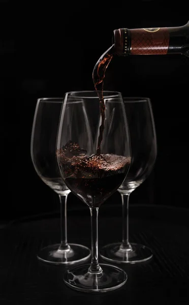 Czerwone Wino Wlewające Się Butelki Szklanki Czarnym Tle — Zdjęcie stockowe