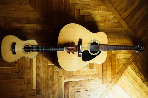 木地板上的黄色吉他和四弦琴的顶视图 — 图库照片